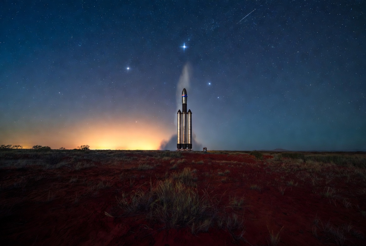 AI-generated concept art (Grok, received 2026-08-07) — The lone rocket standing on the red ground under the southern stars, the flag on its fairing, a launch glow on the horizon
